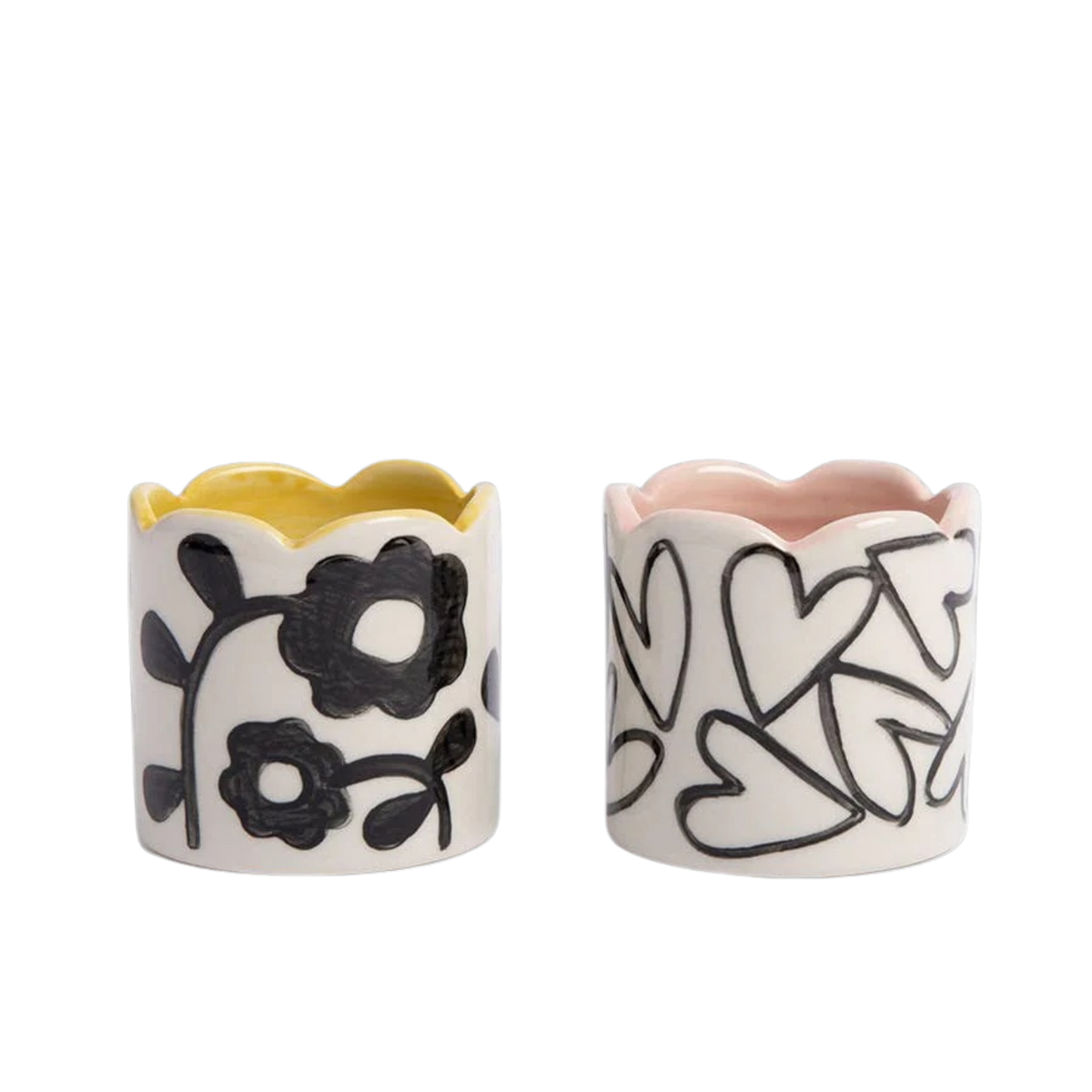 Two ceramic napkin rings with floral and heart designs on a white background