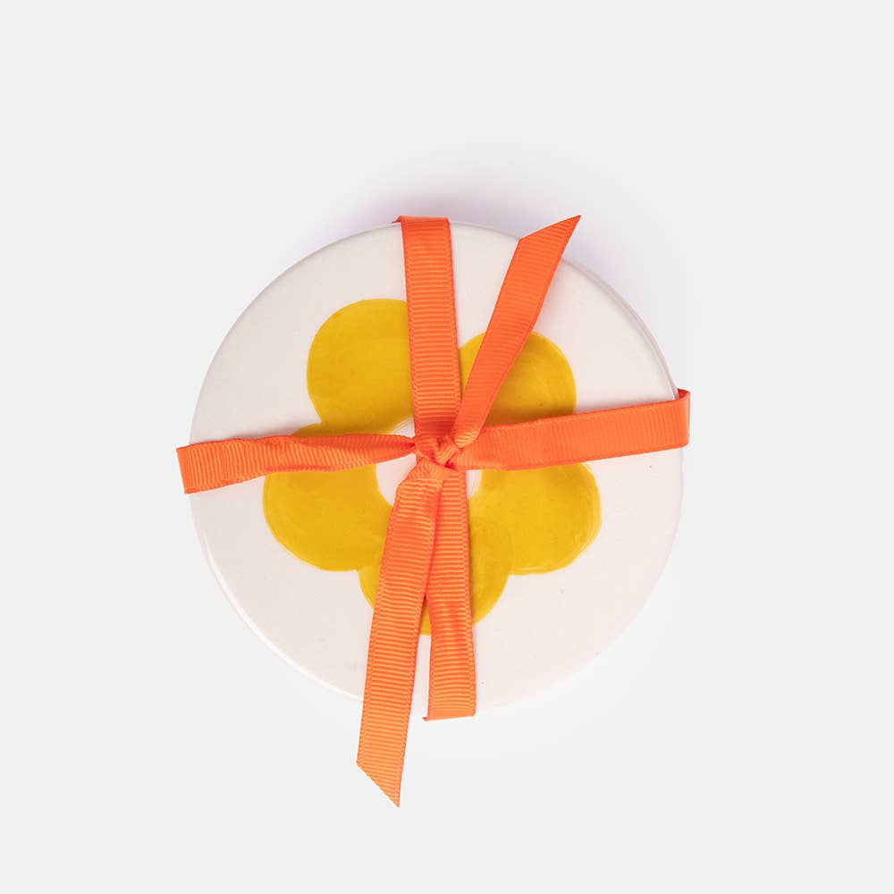 Round white object with a yellow center and orange ribbon on a white background