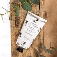 Hand cream tube with label on a wooden surface with eucalyptus leaves