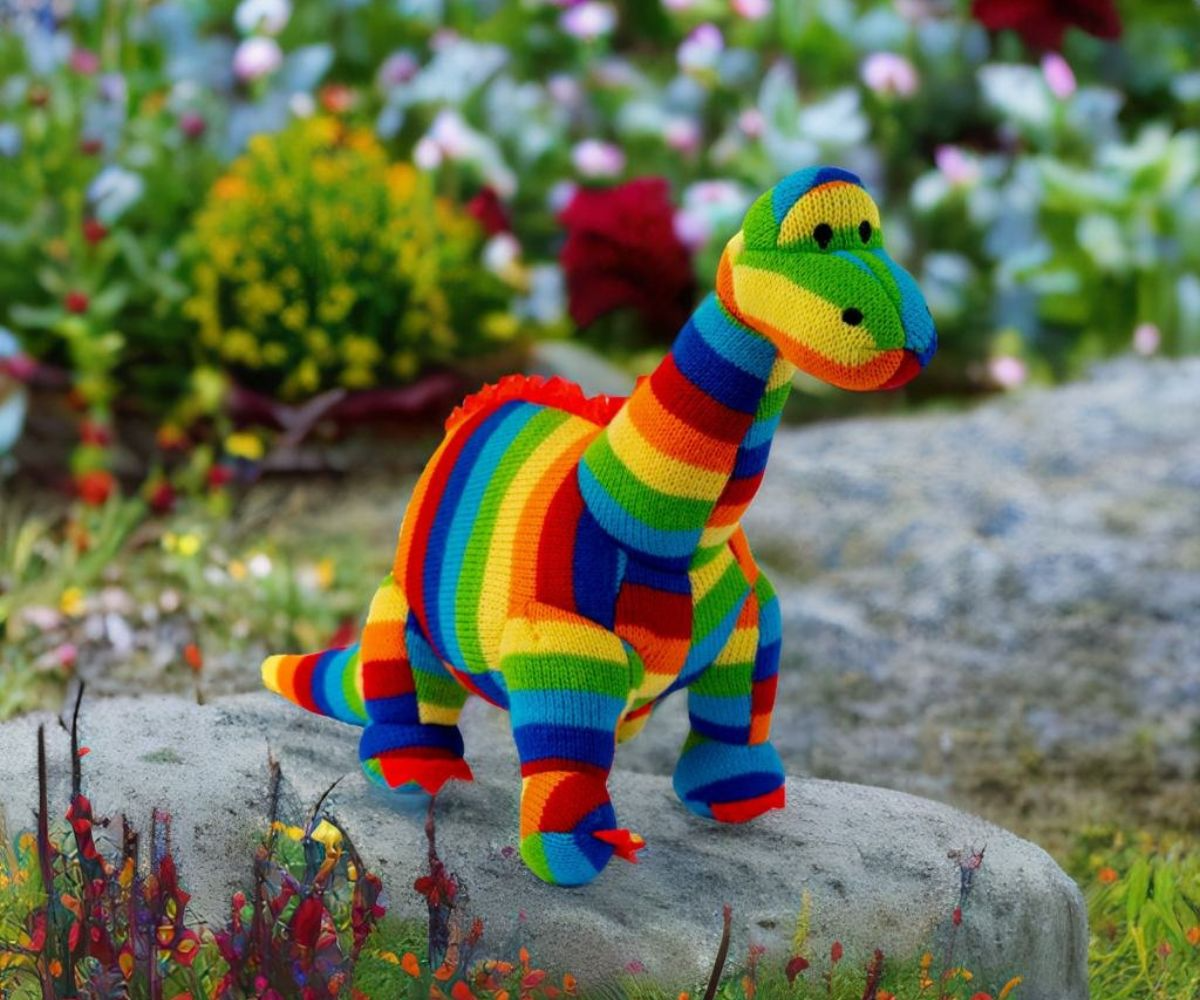 Colorful striped toy dinosaur on a rock with a garden background