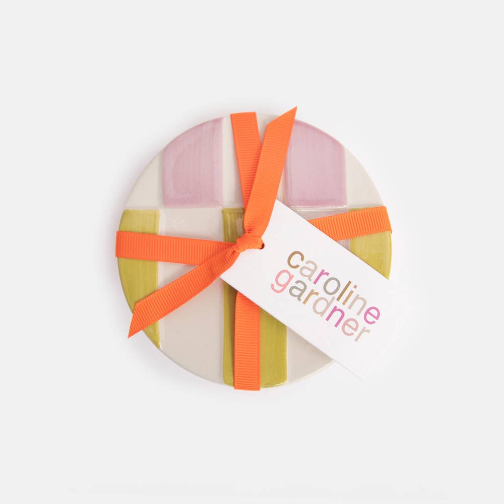 Round gift box with a colorful ribbon and 'caroline gardner' tag on a white background