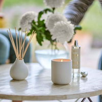 White ceramic Aery candle and diffuser on a table with blurred background
