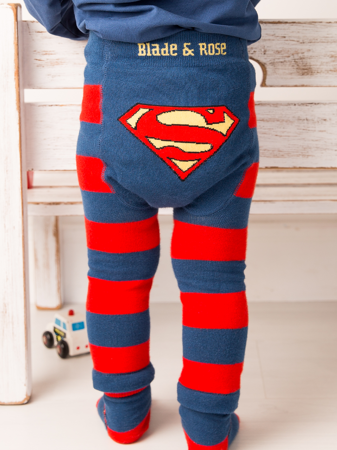 Children's leggings with Superman logo and red and blue stripes, worn by a child.