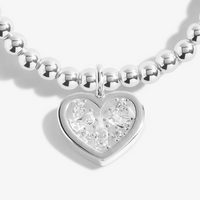 Silver bracelet with a heart-shaped diamond pendant on a white background